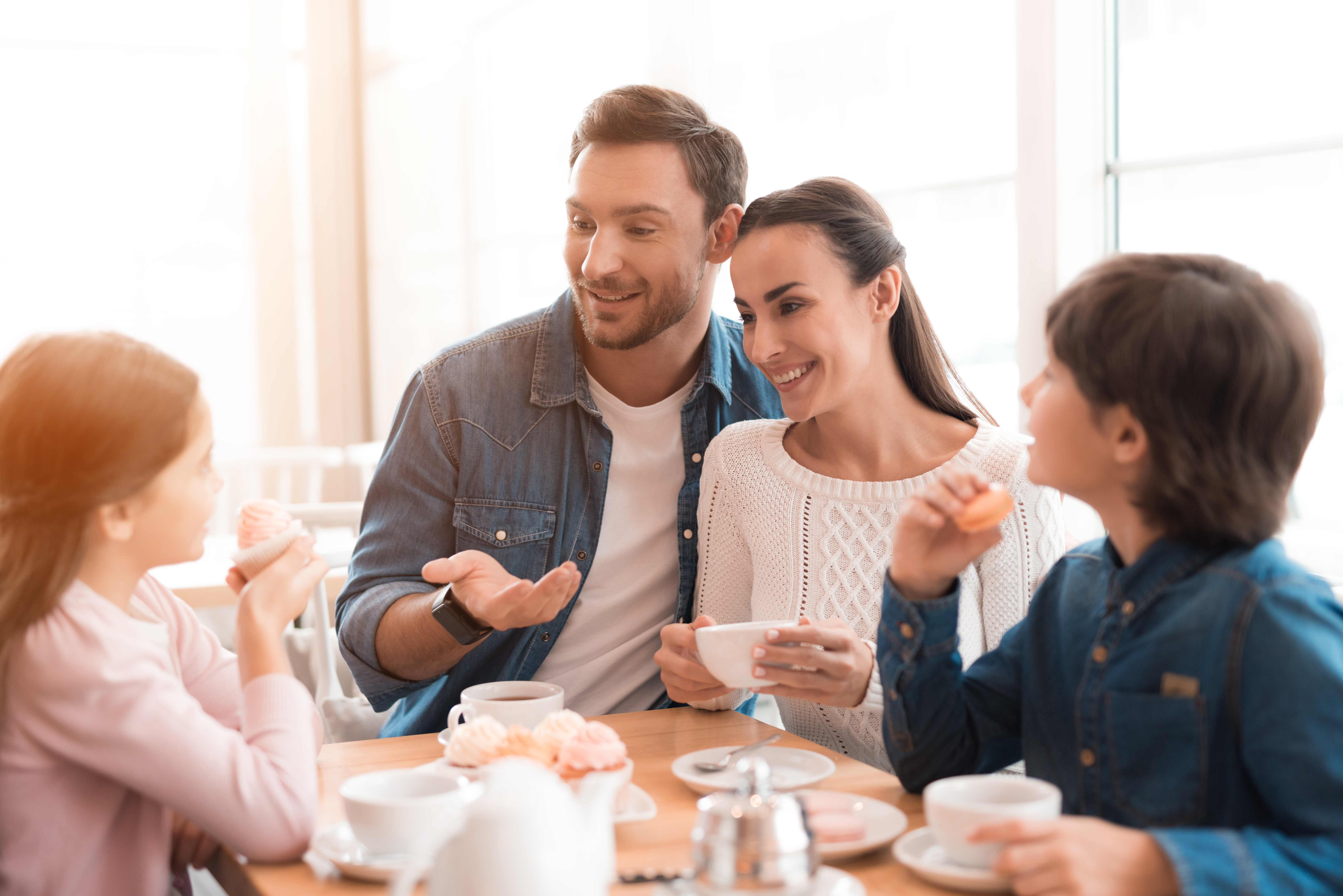 Pai, mãe e filhos sorrindo durando o café da manhã