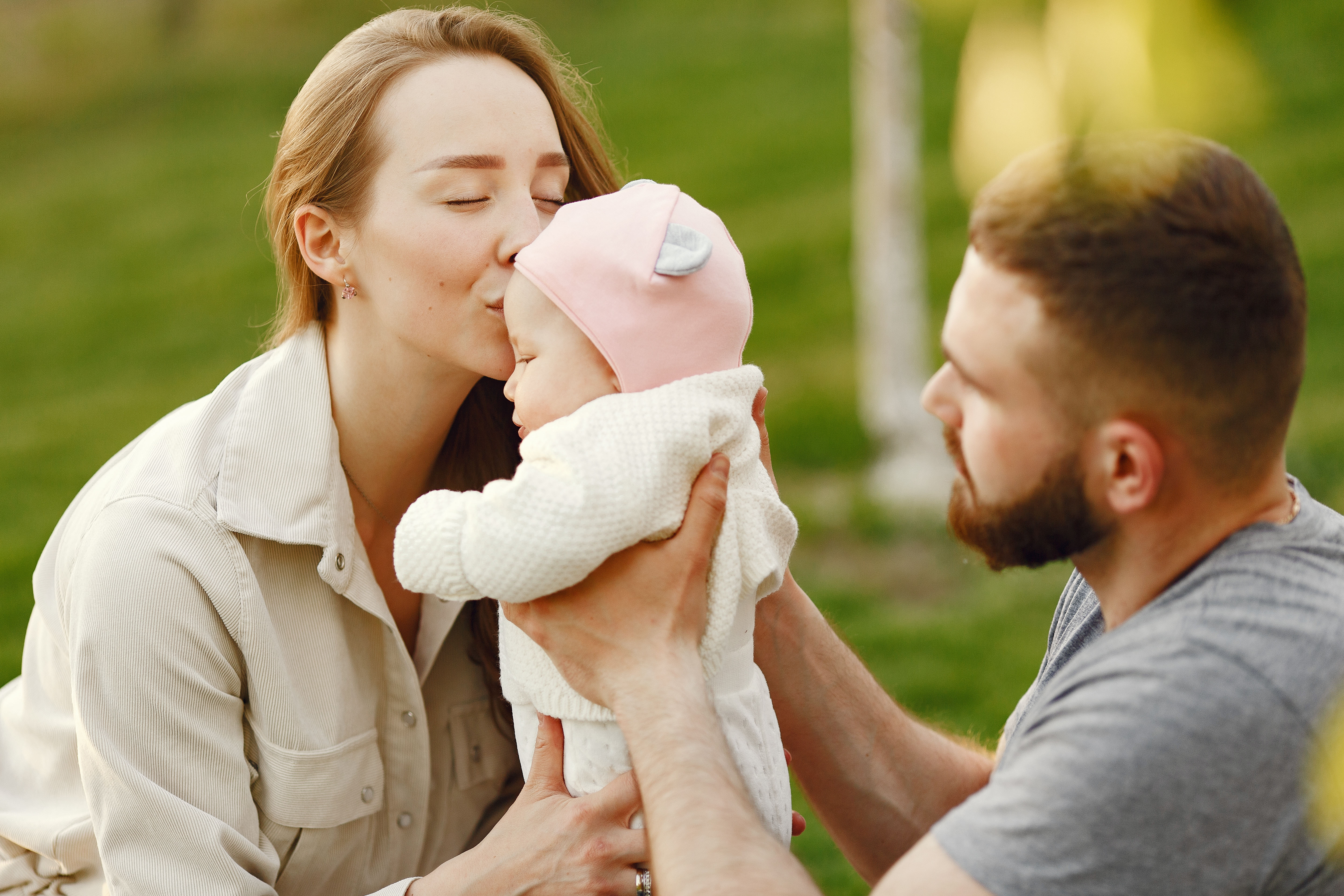 Mãe beijando bebê nos braços do pai